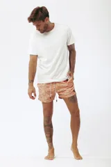 Short de baño salmón con estampado de tablas de surf, cordón ajustable en la cintura y etiqueta lateral de la marca.