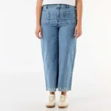 Pantalón jean de tiro alto y pierna ancha, de color azul medio con lavado suave. Presenta bolsillos de parche delanteros, costuras decorativas y un delicado bordado floral blanco en el ruedo.