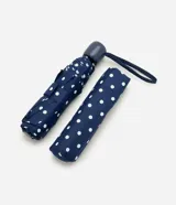 Sombrilla plegable azul marino con estampado de lunares blancos, estructura compacta y asa de muñeca.