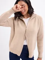 Campera de tejido de punto en color beige, con cierre frontal completo, cuello alto y mangas largas con puños acanalados.