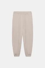 Pantalón de tiro medio con cintura elástica y bajo acabado en puño elástico. Presenta un diseño con tejido efecto arrugado y bolsillos laterales ocultos en costura.