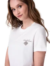 Remera blanca con cuello redondo y mangas cortas, confeccionada con un diseño de corte clásico. Presenta un pequeño estampado gráfico en el pecho con el texto "Caterpillar" y una flor dibujada.