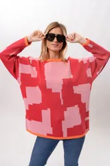 Sweater de punto con diseño geométrico abstracto en tonos rosa y rojo, con cuello redondo y puños y bajo acanalados en color naranja.
