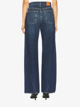 Jean de tiro alto color azul medio lavado, de pierna ancha y recta, con detalles de costuras diagonales.