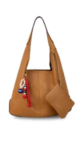Cartera tipo hobo de cuero sintético color suela, con interior espacioso y costuras decorativas frontales. Incluye asa de hombro fija, monedero rectangular colgante a juego y un llavero amuleto con cuentas de madera, ojos turcos y detalles en rojo.