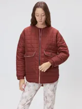 Campera reversible capitoneada con cierre frontal. Un lado es de color negro y el otro es de color beige, ambos con diseño acolchado. Cuenta con cuello redondo, mangas largas y bolsillos laterales.