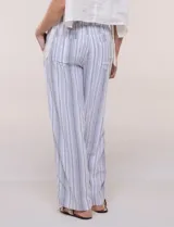 Pantalón de pierna recta y silueta amplia, confeccionado en mezcla de lino y rayón, con diseño a rayas en tonos celestes y blancos. Cuenta con cintura elastizada fruncida, cordón ajustable al frente y bolsillos laterales.