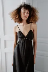 Vestido midi negro con escote en pico, tirantes finos y detalles de bordados y encaje en el escote y el bajo.