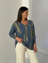 Sweater de punto color azul jean con estampado de pinceladas doradas brillantes, cuello en V y mangas largas.