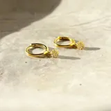 Aros dorados tipo argolla con dije colgante circular con incrustaciones de circonias.