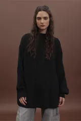 Sweater de punto negro con diseño de trenzas verticales, cuello alto y corte holgado de estilo oversize.