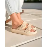 Sandalias chancletas de goma color beige con diseño texturizado en la suela, doble tira ajustable con hebillas y estilo slip-on.