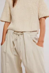 Pantalon de lino y algodon color beige, de tiro bajo, estilo relajado con cintura elastizada ajustable mediante cordón y bolsillos laterales.