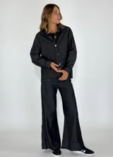 Chaqueta marrón con cuello camisero, cierre frontal con botones, bolsillos de parche y ruedo desflecado.