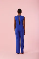 Mono largo de color azul eléctrico, sin mangas, con escote en V profundo y detalle de nudo frontal en la cintura. Presenta un corte recto y fluido en las piernas.