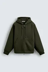 Sudadera de corte relajado confeccionada en tejido técnico con elasticidad y efecto neopreno. Presenta capucha ajustable con cordones, cierre frontal de cremallera de doble dirección, bolsillos tipo canguro y terminaciones en rib.