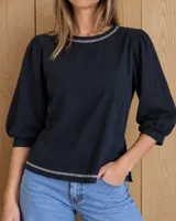 Remera negra de algodón con mangas largas abullonadas y costuras decorativas en contraste en el cuello y el ruedo.