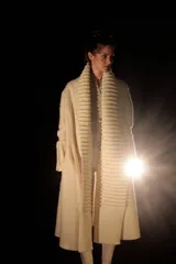 Tapado largo color crudo, confeccionado en lana merino afieltrada. Presenta cuello alto y guarda tejida en el cuello y ruedo. Tiene un estampado de una luna en la espalda.