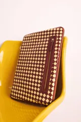 Funda para laptop con diseño tejido a cuadros en tonos marrón y beige.