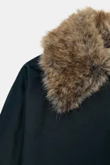 Trench corto de corte recto con capucha y cuello desmontable efecto pelo. Presenta cierre frontal con botones, bolsillos laterales y mangas largas con trabillas en los puños.