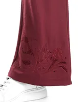 Pantalón tipo jogger de corte ancho y fluido, color bordó, con cintura elástica, bolsillos laterales y detalle de bordado floral calado en el ruedo.