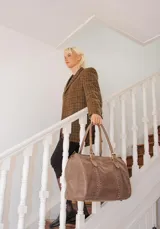 Bolso de mano tipo shopper marca Amadea, confeccionado en cuero con acabado desgastado. Presenta detalles de costuras decorativas verticales, correas con hebillas metálicas doradas y logo grabado al frente.