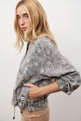 Bomber de tela liviana color beige con textura sutil, cierre frontal completo, mangas largas con puños elásticos y cordón ajustable en el ruedo.