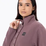 Buzo polar de microfleece color malva, con cuello alto, apertura frontal media con botones a presión y tapeta de nylon. Presenta bolsillos laterales reforzados en nylon y puños con sujeción elástica.