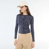 Camiseta de manga larga en tejido de punto acanalado color azul marino con estampado floral pequeño en tonos rosados. Presenta cuello redondo con cierre frontal de botones tipo henley.