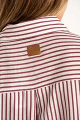 Camisa de corte oversize con estampado de rayas verticales, cuello clásico, cierre frontal con botones y bolsillo en el pecho. Presenta mangas largas con puños abotonados y un diseño fluido.