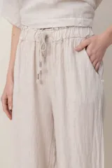 Pantalon de lino color azul, de corte ancho y relajado, con cintura elastizada ajustable mediante cordón y bolsillos laterales. Presenta detalles de alforzas en los bajos.