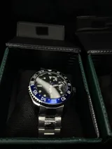 Reloj Rolex Submariner "Batman" con bisel giratorio unidireccional negro y azul, esfera negra con índices luminiscentes, lupa sobre la ventana de fecha y malla de acero inoxidable.