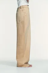 Jeans de tiro medio y corte ancho, confeccionados en denim con lavado estilo vintage de efecto desgastado. Presentan diseño de doble cinturilla superpuesta, cinco bolsillos tradicionales, trabillas para cinto y cierre frontal con cremallera y botón metálico.