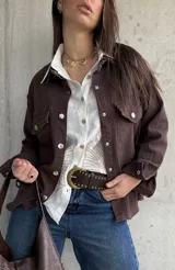 Sobrecamisa de gabardina color marrón chocolate, de corte holgado, con bolsillos con solapa en el pecho, mangas largas y cierre frontal de botones metálicos.