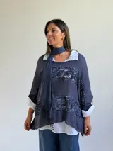 Sweater de punto azul con diseño holgado, que incorpora paneles de encaje floral en el frente y los laterales. Presenta un estilo superpuesto con cuello redondo y mangas largas con puños vueltos.