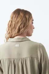 Camisa de manga larga en color celeste, con diseño de corte relajado, cuello clásico y detalle de tablas verticales en el frente.