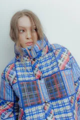 Campera puffer con estampado a cuadros en tonos azul, rojo, amarillo y blanco. Diseño capitoneado a mano y forro interior verde. Corte holgado. Ideal para usar con un look casual.