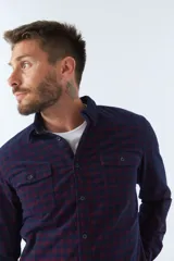 Camisa de manga larga confeccionada en pana de algodón con estampado de cuadros en tonos azul y bordó. Presenta cuello clásico, cierre frontal con botones y ajuste regular.