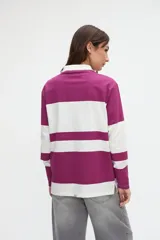Remera polo de manga larga de algodón lavado, con diseño de rayas horizontales anchas en azul y blanco, cuello y cartera de botones en color blanco, y pequeños tajos laterales.