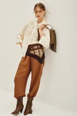 Camisa de viscosa color crema, con cuello mao y cierre frontal de botones. Presenta un delicado bordado floral en el frente y mangas tres cuartos con puños rectos.