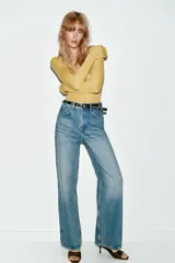 Jeans de tiro alto color azul claro, con cinco bolsillos y pernera recta que se estrecha hacia el tobillo. Incluye un cinturón negro con detalles metálicos. Cierre frontal con cremallera y botón.