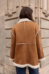 Tapado estilo gamulán con interior de corderito sintético, cuello amplio, bolsillos delanteros y cierre frontal con alamares. Diseño de corte oversized con terminaciones a contratono.