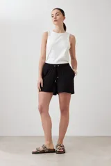 Short negro de corte recto con cintura elastizada y cordón ajustable. Presenta bolsillos laterales y detalle de costuras verticales en el frente.