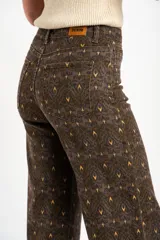 Jean flared wide leg de tiro medio con estampado geométrico en tonos marrón, verde militar y amarillo.