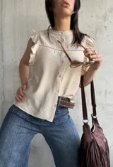 Blusa beige con cuello mao, mangas cortas con volados y cierre frontal con botones.