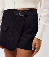 Short pollera de sastrería con diseño tipo envelope y estampado de raya diplomática. Cuenta con un cinturón lateral integrado y un calce estructurado.