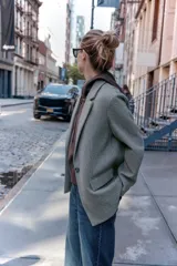 Blazer de corte recto y diseño minimalista, confeccionado en tejido de paño suave color beige. Presenta cuello con solapas clásicas, cierre frontal con un solo botón y dos bolsillos delanteros con solapa.