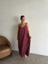 Vestido largo de crepe con estampado de lunares negros sobre fondo blanco. Presenta un diseño de corte holgado con breteles finos y escote redondeado.