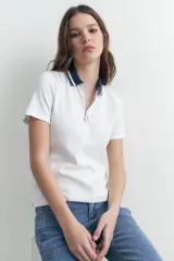 Remera blanca de manga corta con cuello polo azul marino y cierre metálico.
