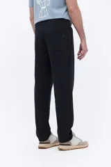 Pantalón de jogging con corte recto y ajuste relajado, confeccionado en tejido de algodón y poliéster. Cuenta con cintura elástica con cordón de ajuste y bolsillos laterales funcionales.